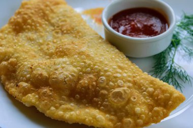 Hamurda soğan ve baharat olan kuzu eti. Sauc ile Cheburek