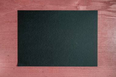 Koyu ahşap bir masada temiz, siyah bir kağıt. eski tahta arkaplan.