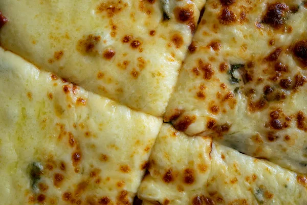 Dilimlenmiş pizza yüzeyine yakın çekim. Domatesli ve peynirli ev yapımı vejetaryen pizza..