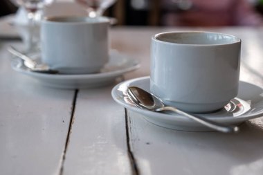 Kafedeki kırık beyaz ahşap bir masada bir çift beyaz kahve fincanı..
