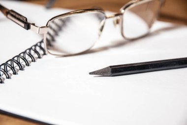 Ofisin arkaplan resmi, not defteri ve malzemeler ahşap masa, ince bardaklar ve siyah kalem..