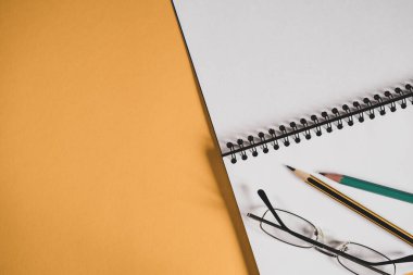 Not defteri, gözlükler ve sarı renkli kalemlerle dolu bir ofis masası. Ev işyerinin düz yatağı. Üst görünüm.