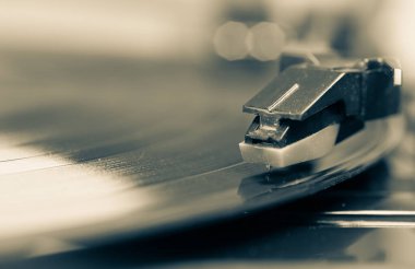 Vinil plaklı bir pikap. Nostaljik ekipmanlar. Retro müzik. Bir fonograf iğnesinin yakın çekimi. Gramofon kayıtlarındaki yansımalar.