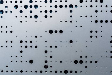Delikli metal levha. Gri metal levha. Ön cephe kapağı. Geometrik desenler. Modern mimari. Kara delikler. İlginç bir temel.