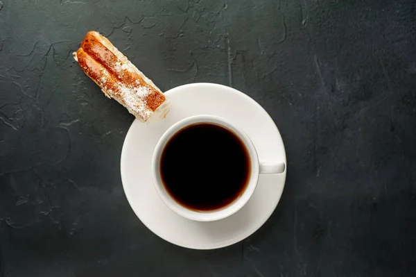 cup and coffee with bakery product on a dark background