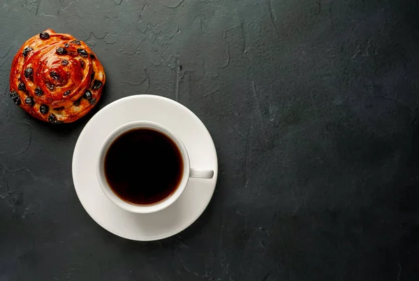 cup and coffee with bakery product on a dark background