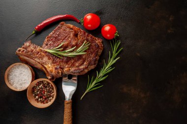 Biberiyeli ızgara biftek, arka planda sebze ve baharatlar.