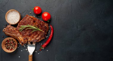 Biberiyeli ızgara biftek, arka planda sebze ve baharatlar.