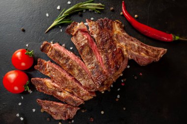 Siyah taş arka planda dilimlenmiş biftek.