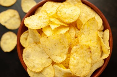 Siyah taş arka planda patates cipsi, abur cubur..