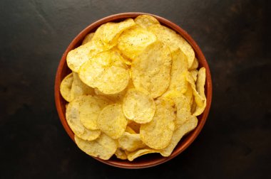 Siyah taş arka planda patates cipsi, abur cubur..