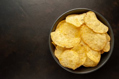 Siyah taş arka planda patates cipsi, abur cubur..
