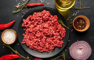 Siyah arka planda çiğ et, sebze, tuz ve yağ..