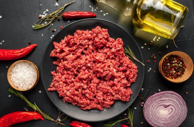 Siyah arka planda çiğ et, sebze, tuz ve yağ..