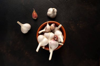 Sarımsak kafalar siyah arka planda kahverengi kasede servis edilir.