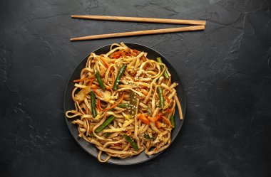 Asyalı baharatlı makarna kasesi ve siyah taş kaplama yemek çubukları.