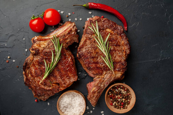 Beef steaks with spices on black stone background