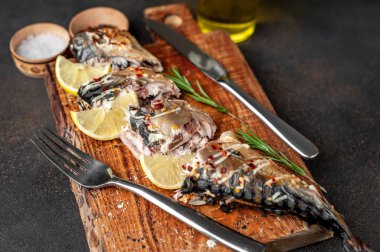 Tahtada servis edilen limonlu ve çatal bıçaklı fırında uskumru.