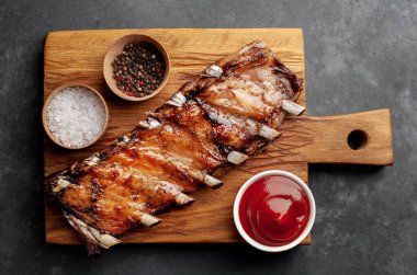 Ahşap kesme tahtasındaki domuz pirzolası, baharat ve bbq sosu.