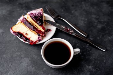 Çatalla servis edilen dilimlenmiş sünger keki ve kahve tabağında bıçak. 