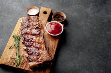 Baharatlı ızgara domuz pirzolası ve ahşap tahtada barbekü sosu.