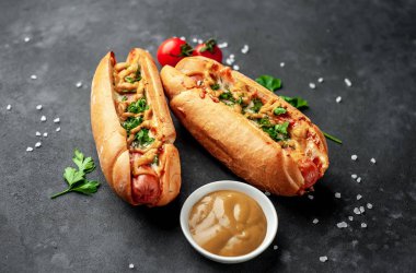 Granit masada bir kase hardal ve olgun domatesle servis edilen sosisliler.