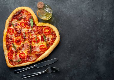 Zeytinyağı, çatal ve bıçaklı kalp şeklinde pizza. Sevgililer Günü için sakin bir hayat.