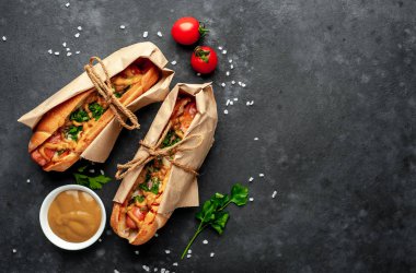 Granit masada bir kase hardal ve olgun domatesle servis edilen sosisliler.