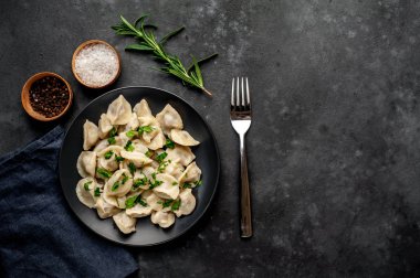 Baharat ve çatalla servis edilen siyah tabakta lezzetli hamur tatlısı.