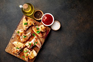 Tahta tahtada servis edilen tavuk kanatları, bbq sosu, limon, şişede zeytinyağı ve baharatla dolu.