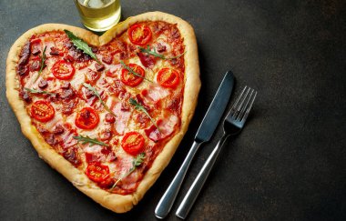 Zeytinyağı, çatal ve bıçaklı kalp şeklinde pizza. Sevgililer Günü için sakin bir hayat.