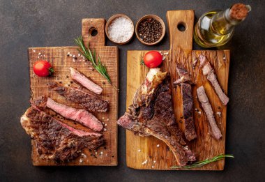 Baharatlı ve zeytinyağlı ahşap tahtalarda servis edilen et biftekleri.