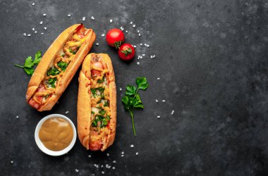 Granit masada bir kase hardal ve olgun domatesle servis edilen sosisliler.