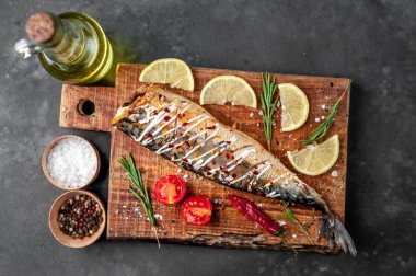 Tahtada servis edilen limonlu, domatesli ve biberiyeli fırında uskumru.