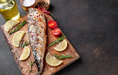 Tahtada servis edilen limonlu, domatesli ve biberiyeli fırında uskumru.