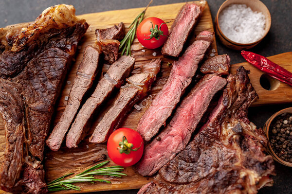 Sliced beef steak with tomatoes on wooden board