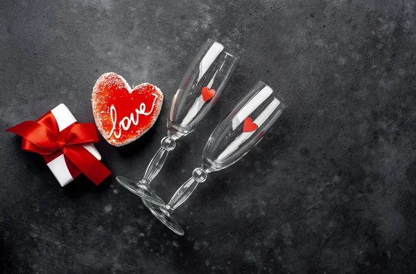 Valentines day still life - Empty wine glasses with red cake, gift box and hearts on granite table.