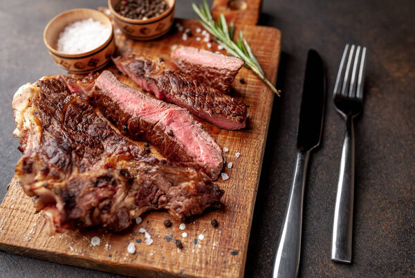 Sliced steak on board with cutlery