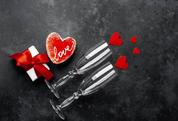 Valentines day still life - Empty wine glasses with red cake, gift box and hearts on granite table.