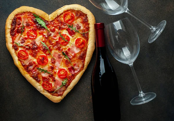 Heart shaped pizza with wine bottle and glasses. Still life for Valentines day.