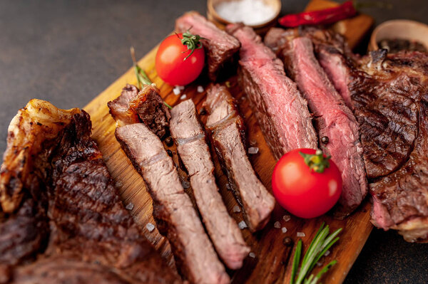 Sliced beef steak with tomatoes on wooden board