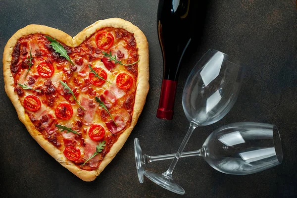 Heart shaped pizza with wine bottle and glasses. Still life for Valentines day.
