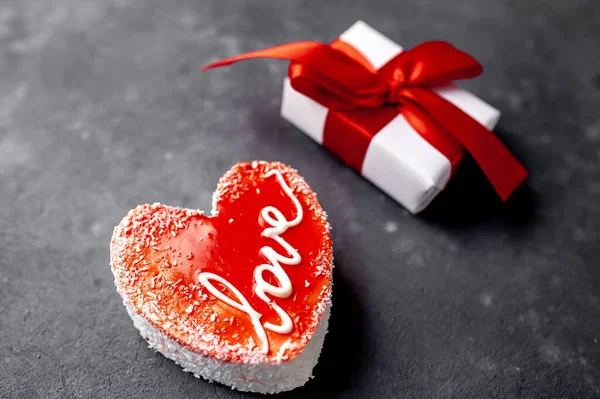 Valentines day still life - red heart shaped cake with gift box on granite table.