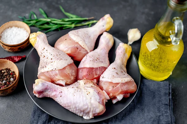 Raw chicken legs with spices and oil on table