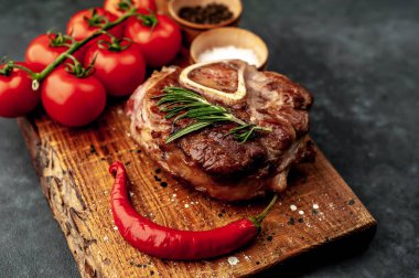 grilled steak, with tomatoes and spices on a stone background.
