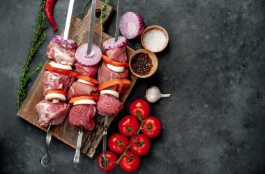 Çiğ et şişlerinin üst görüntüsü. Arka planda sebzeli ve baharatlı ızgara et..