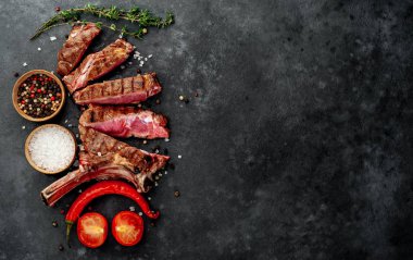 steak - sliced, grilled beef tomahawk with spices on a stone background. 