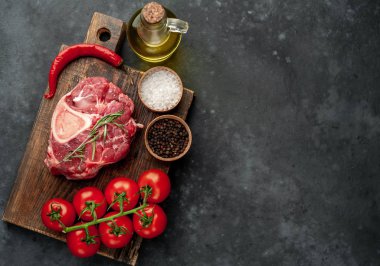 raw beef steak with tomatoes and spices on a stone background.