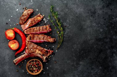 steak - sliced, grilled beef tomahawk with spices on a stone background. 