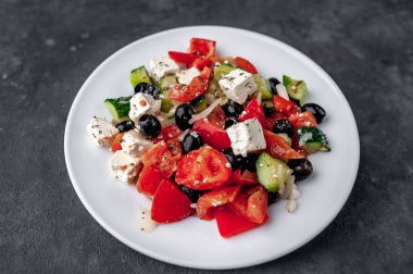 Greek salad in a white plate on a stone background